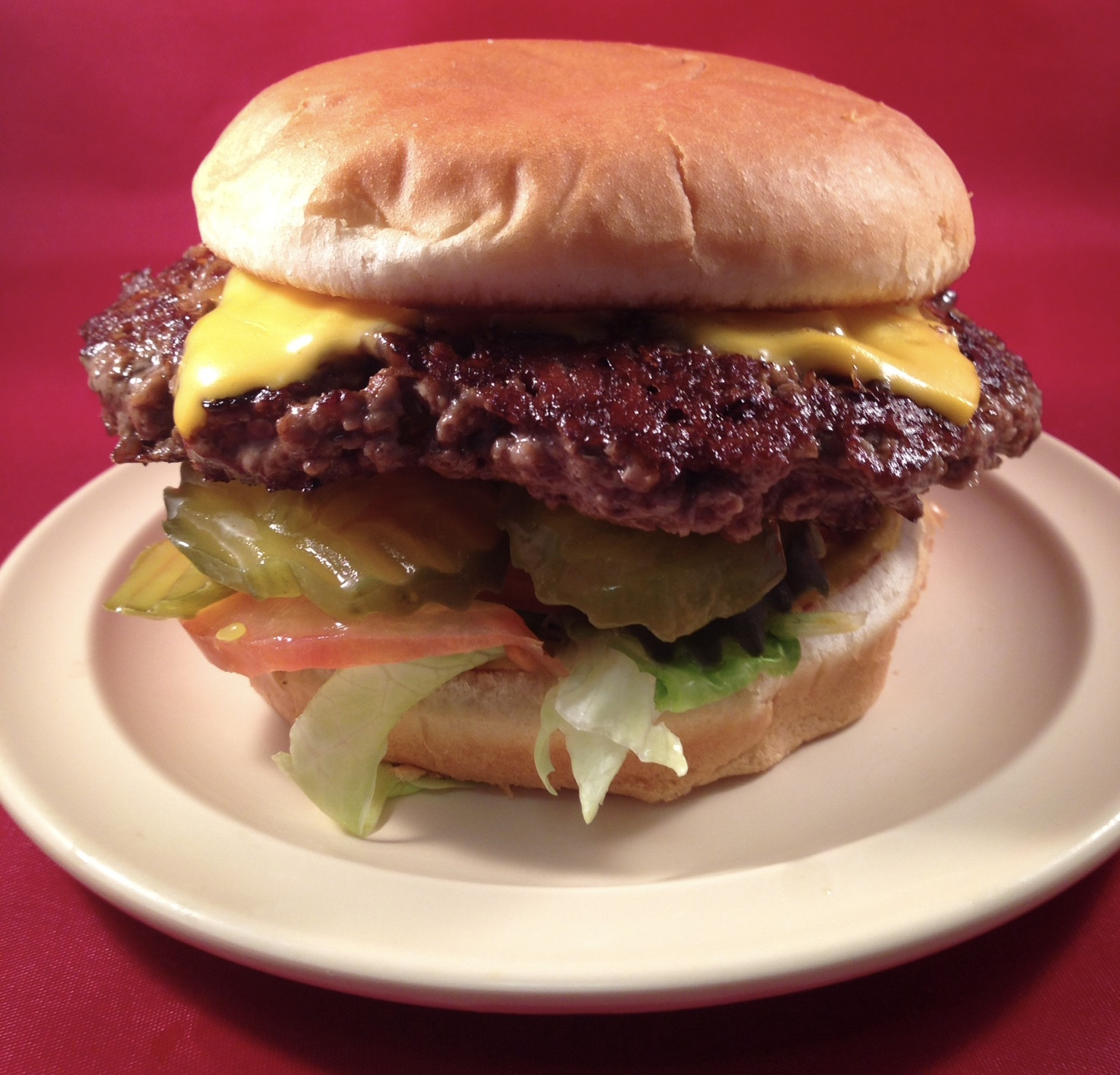 Single cheeseburger with lettuce, tomato and pickles
